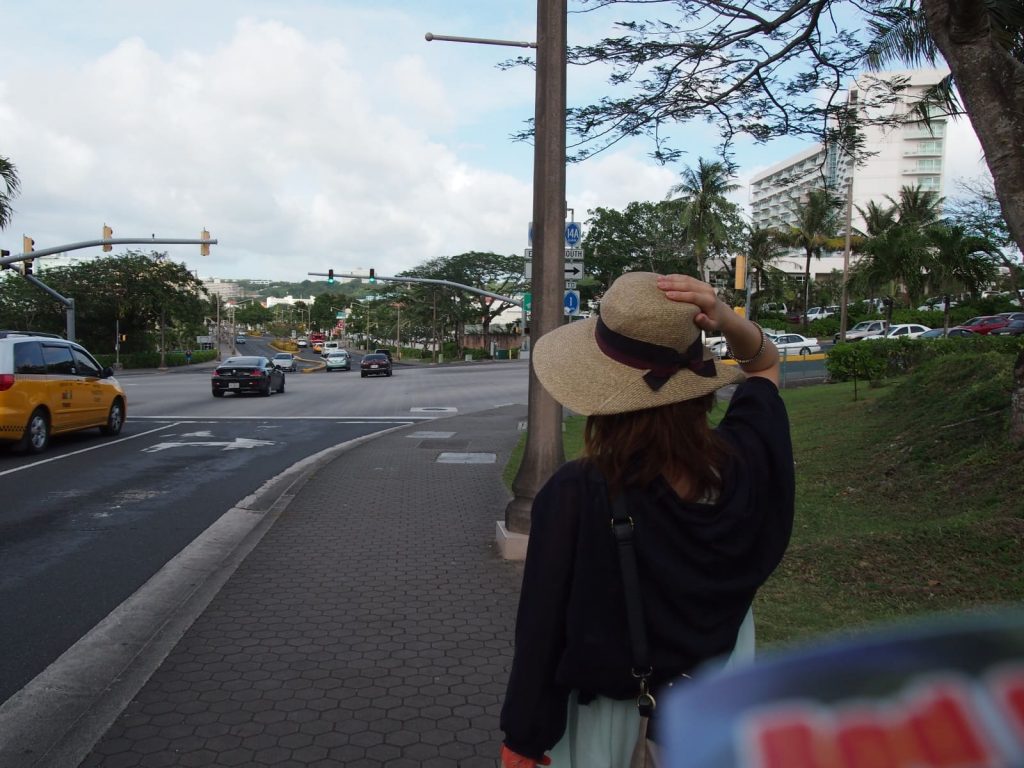 歩道に帽子を被った女性が佇んでいる写真の画像