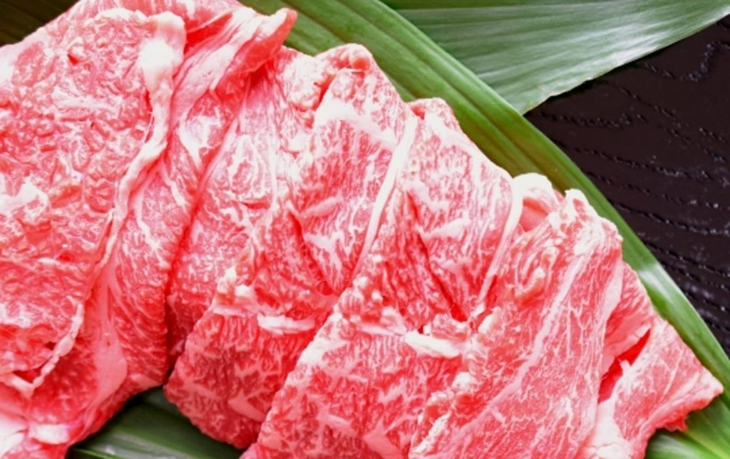 笹の葉の上に載せられた調理前の牛肉の写真の画像