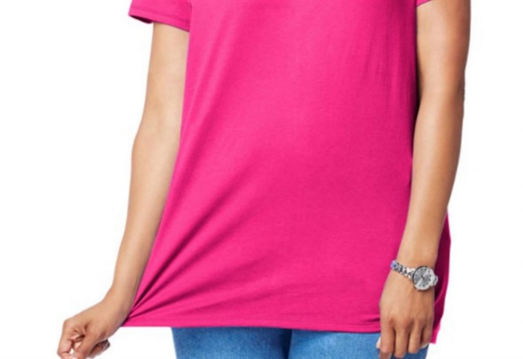 ピンクのTシャツを着た女性がTシャツの裾を持って立っている画像