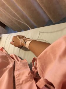 点滴を打ってベッドの上で休んでいる女性の腕のアップの写真の画像