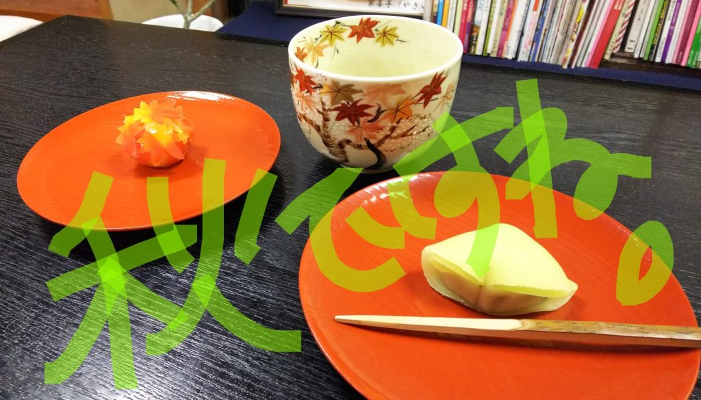 オレンジ色のお皿に乗った練りきりともみじ柄の湯呑が並んだ写真の画像