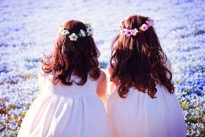 海岸で子ども2人が背を向け並んで座っている画像