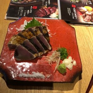 赤い器に盛られたカツオのたたきの写真の画像
