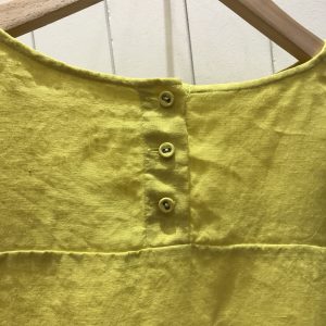 ハンガーに掛かった黄色っぽい服の写真の画像