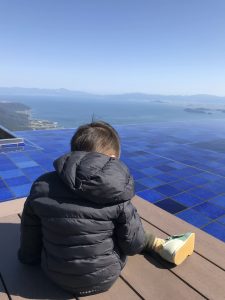 座った子供の後ろ姿ときれいな景色の写真の画像