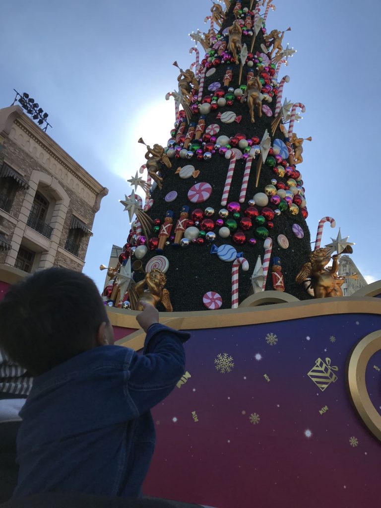 大きなクリスマスツリーの足元に立つ子供の後姿の写真の画像