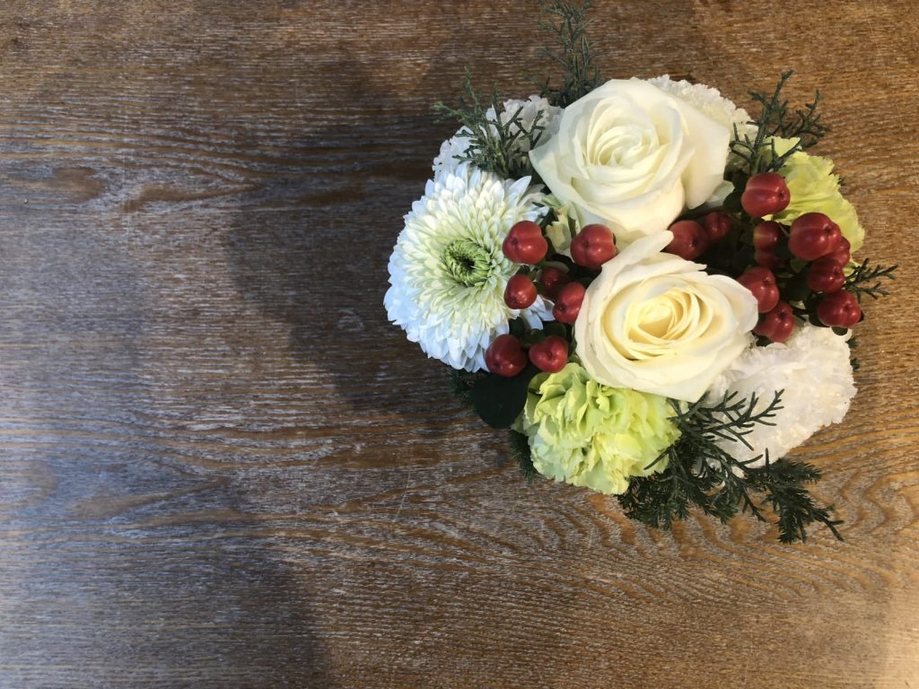 木製のテーブルに置かれた白っぽい花のブーケの写真の画像