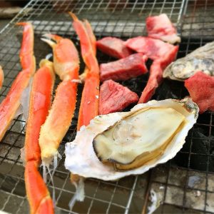 焼き網の上のカニの脚とカキと肉の写真の画像