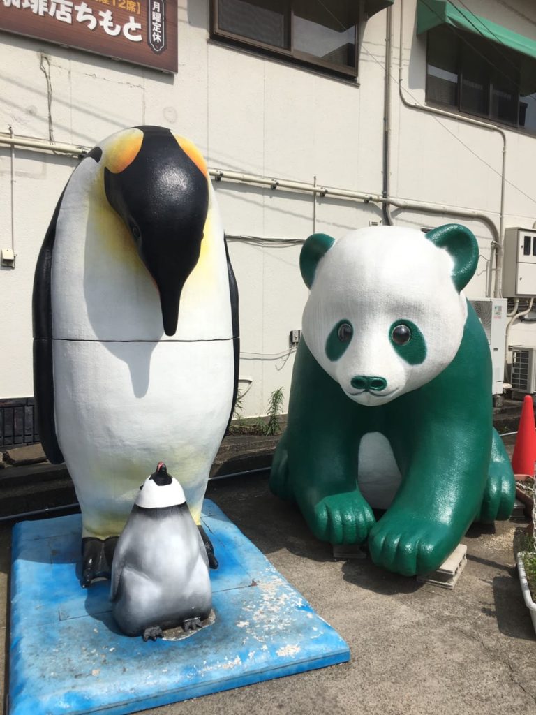 ペンギンの親子と緑色のパンダのモニュメントの写真の画像