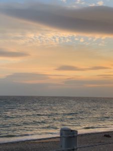 薄くオレンジに色づいた空と海の写真の画像